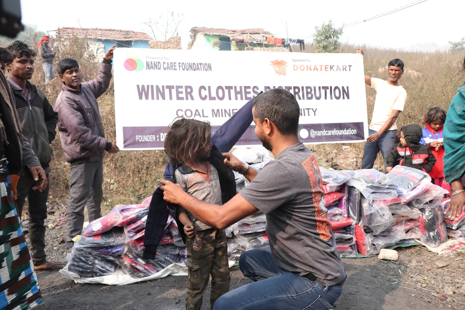 Volunteer helping a child try on winter clothing in a coal mining community