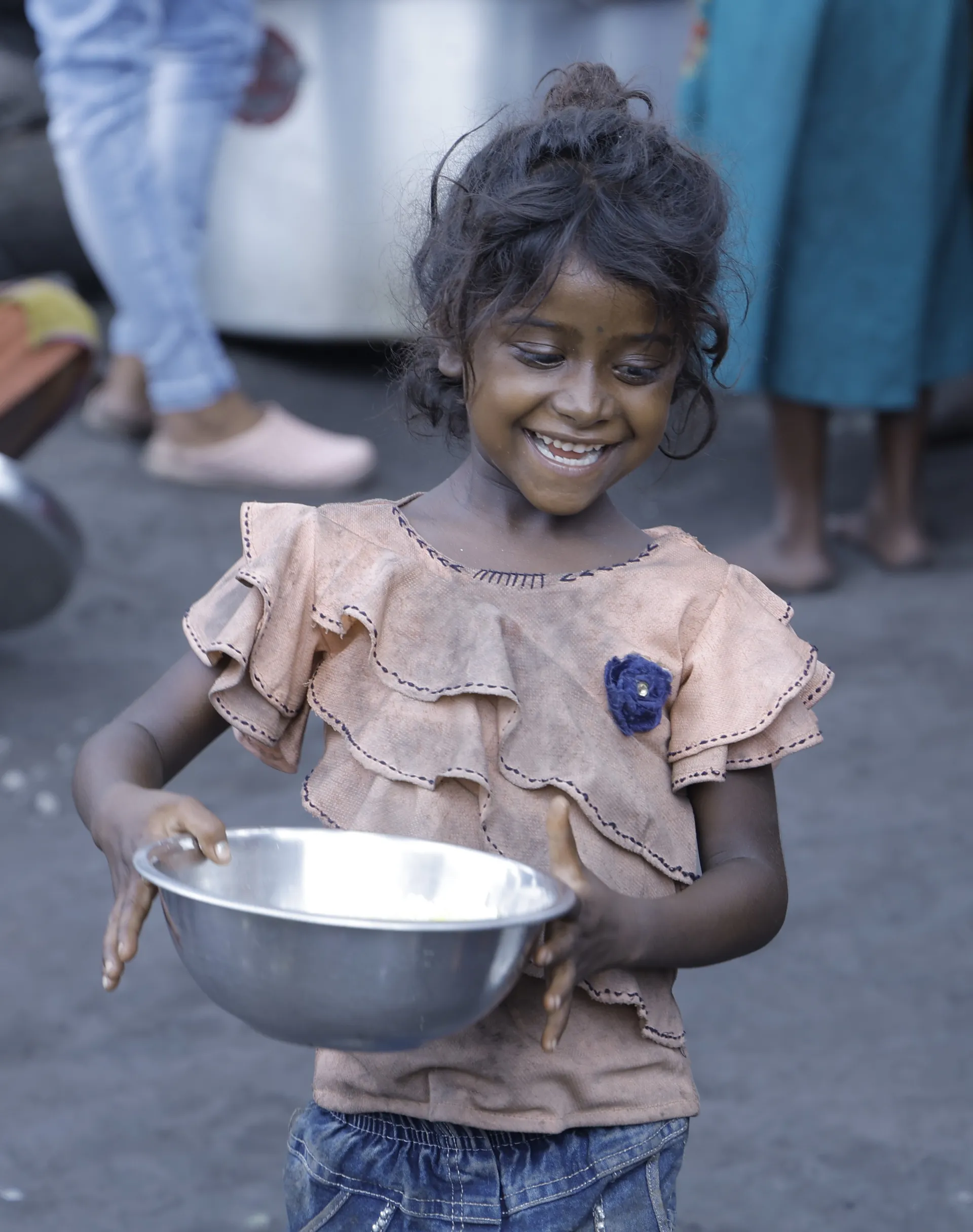 Smiling girl holding a steel bowl of food