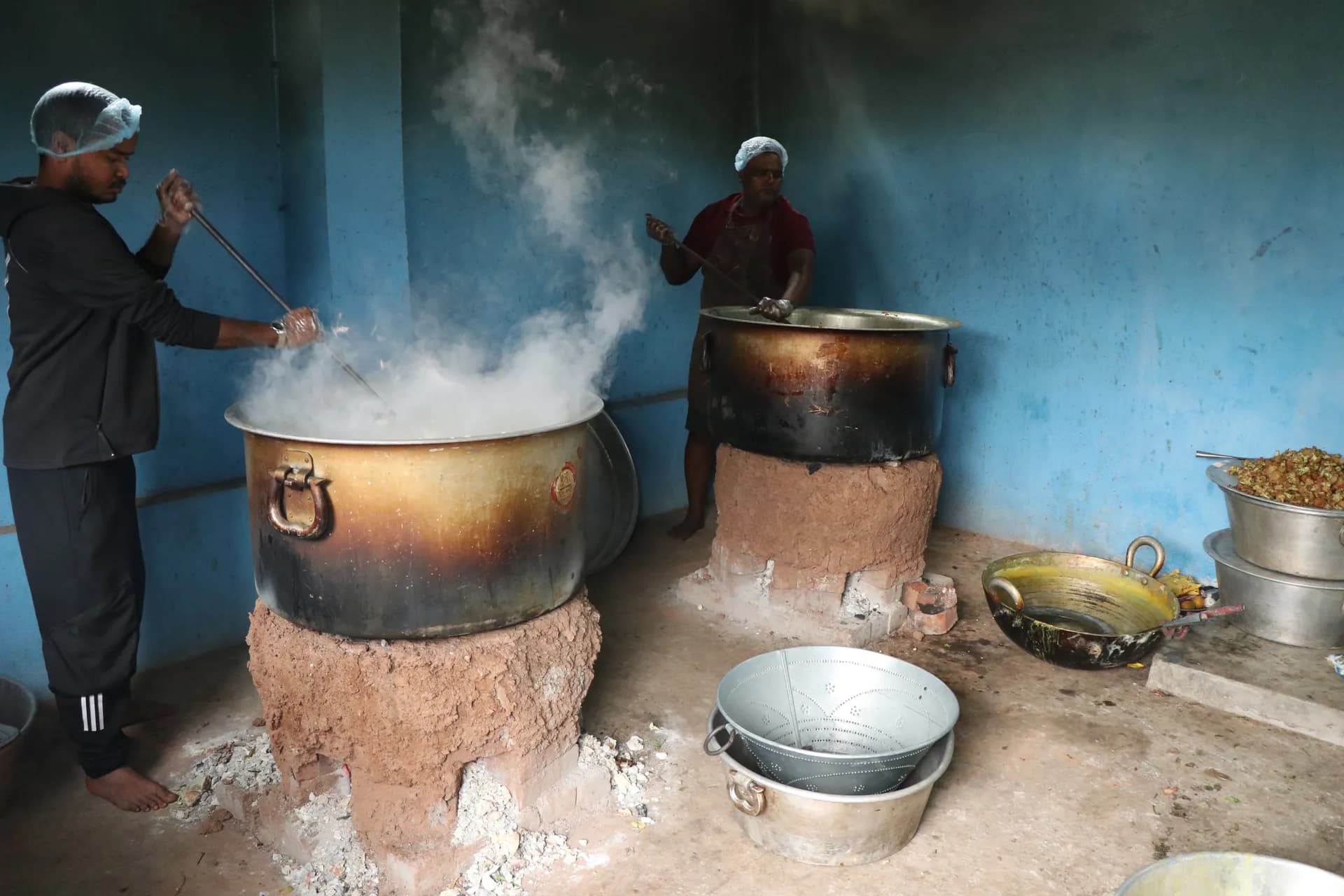 Volunteers cooking a large pot of meals over a wood fire
