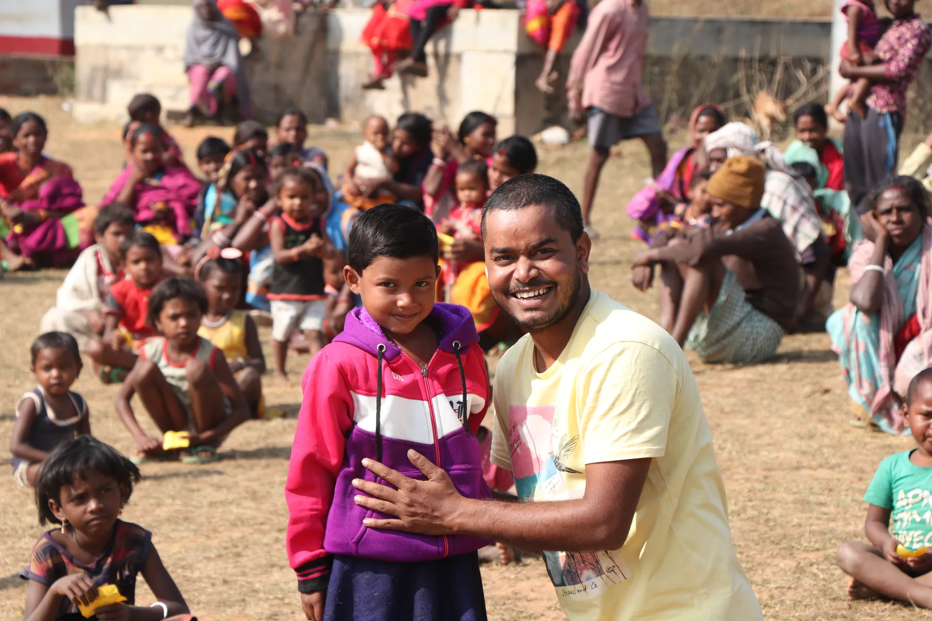 Volunteer with a child in a pink hoodie at a winter clothes distribution