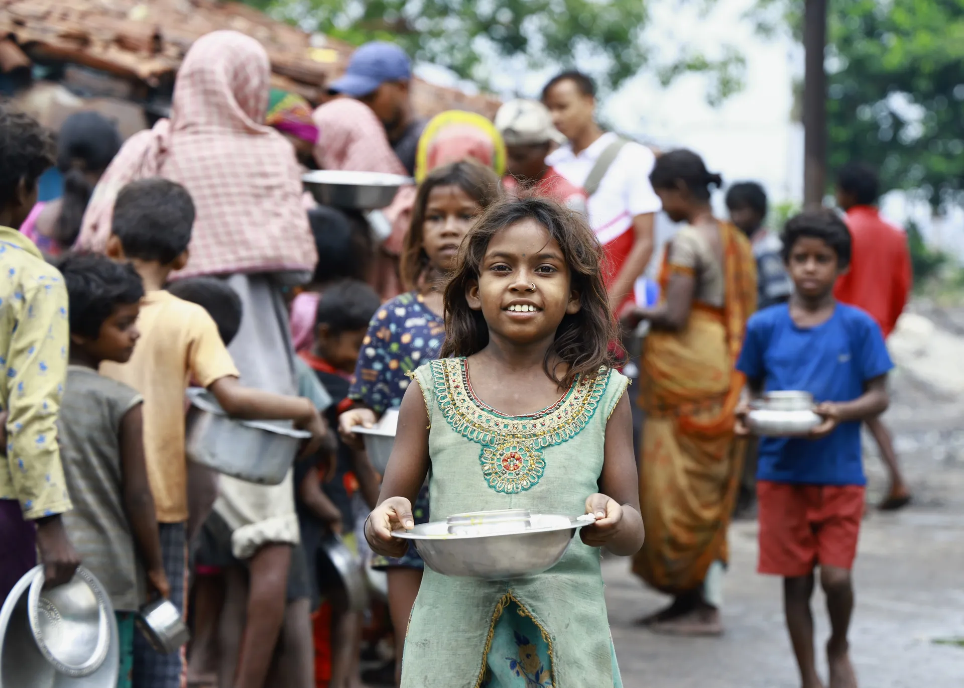 Girl holding a steel plate for a hot meal in a tribal community