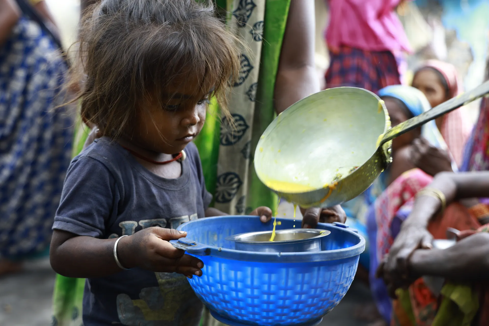 Toddler holding a blue bowl as a hot meal is served
